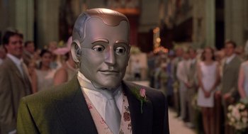 Movie still from “Bicentennial Man” (1999), directed by Chris Columbus – A man in a suit and tie wearing a robot head; Close Up shot, High angle