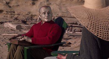 Movie still from “Bicentennial Man” (1999), directed by Chris Columbus – A man sitting in a chair wearing a red sweater; Medium shot, Over the shoulder angle