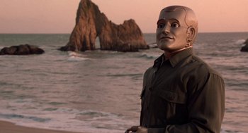 Movie still from “Bicentennial Man” (1999), directed by Chris Columbus – A man wearing a mask standing in front of a body of water; Medium shot, Low angle
