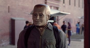 Movie still from “Bicentennial Man” (1999), directed by Chris Columbus – A man with a fake head is standing outside; Close Up shot, Over the shoulder angle