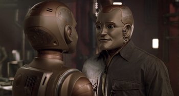Movie still from “Bicentennial Man” (1999), directed by Chris Columbus – Two robots are looking at each other in a room; Close Up shot, Over the shoulder angle