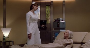 Movie still from “Bicentennial Man” (1999), directed by Chris Columbus – A woman standing next to an older man in a hospital bed; Medium shot, Low angle