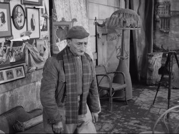 Movie still from “Big Deal on Madonna Street” (1958), directed by Mario Monicelli – An old man standing in front of a chair; Wide shot, High angle
