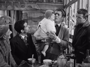 Movie still from “Big Deal on Madonna Street” (1958), directed by Mario Monicelli – A man holding a baby in his arms while two other men look on; Medium shot, Over the shoulder angle