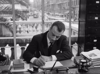 Movie still from “Big Deal on Madonna Street” (1958), directed by Mario Monicelli – A black and white photo of a man writing on a piece of paper; Medium shot, Low angle
