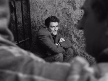 Movie still from “Big Deal on Madonna Street” (1958), directed by Mario Monicelli – A black and white photo of a man sitting on the ground; Medium shot, Over the shoulder angle