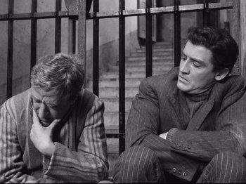 Movie still from “Big Deal on Madonna Street” (1958), directed by Mario Monicelli – A couple of men sitting next to each other on the ground; Medium shot, High angle