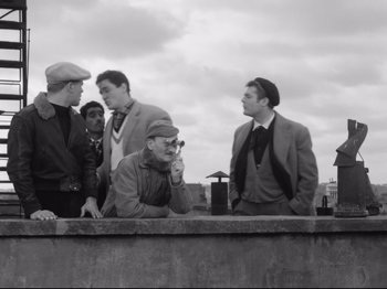 Movie still from “Big Deal on Madonna Street” (1958), directed by Mario Monicelli – A group of men standing on top of a concrete wall; Medium shot, Low angle