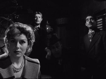 Movie still from “Big Deal on Madonna Street” (1958), directed by Mario Monicelli – A group of men and a woman standing next to each other in a room; Medium shot, Low angle