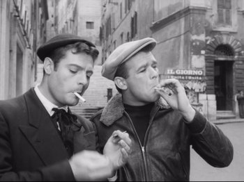 Movie still from “Big Deal on Madonna Street” (1958), directed by Mario Monicelli – A couple of men standing next to each other on a street; Medium shot, Low angle