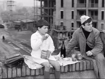 Movie still from “Big Deal on Madonna Street” (1958), directed by Mario Monicelli – Two people sitting on a wall eating food; Medium shot, High angle