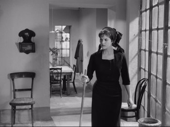 Movie still from “Big Deal on Madonna Street” (1958), directed by Mario Monicelli – A woman holding a mop while standing in a room; Medium shot, High angle