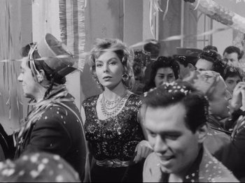 Movie still from “Big Deal on Madonna Street” (1958), directed by Mario Monicelli – A woman in a crowd of people wearing a dress; Medium shot, Low angle