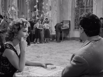 Movie still from “Big Deal on Madonna Street” (1958), directed by Mario Monicelli – A woman sitting at a table in front of another woman; Medium shot, Over the shoulder angle