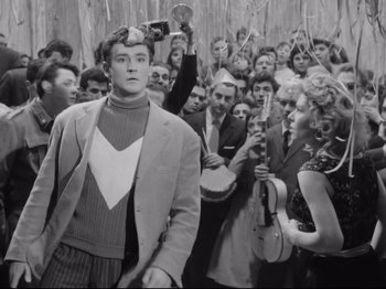 Movie still from “Big Deal on Madonna Street” (1958), directed by Mario Monicelli – A group of people gathered around a man in front of a crowd; Medium shot, High angle