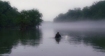 Movie still from “Big Fish” (2003), directed by Tim Burton – A person in a body of water with trees in the background; Extreme Wide shot, Over the shoulder angle