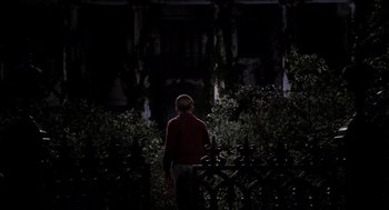 Movie still from “Big Fish” (2003), directed by Tim Burton – A boy standing in front of a building at night; Wide shot, Low angle