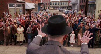 Movie still from “Big Fish” (2003), directed by Tim Burton – An older man in a hat is waving to a crowd; Wide shot, High angle