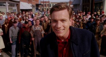 Movie still from “Big Fish” (2003), directed by Tim Burton – A man standing in front of a group of people; Medium shot, Over the shoulder angle