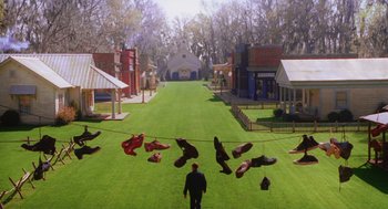 Movie still from “Big Fish” (2003), directed by Tim Burton – A man standing on a grass covered field with a bunch of umbrellas; Extreme Wide shot, High angle