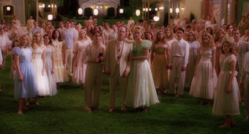 Movie still from “Big Fish” (2003), directed by Tim Burton – A group of people standing in front of each other on a field; Wide shot, High angle