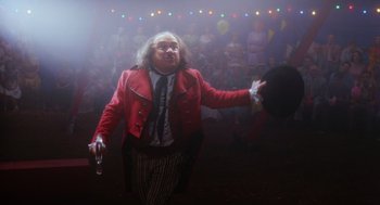 Movie still from “Big Fish” (2003), directed by Tim Burton – A man in a red jacket is holding a hat; Medium shot, Low angle