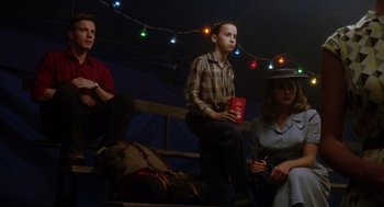 Movie still from “Big Fish” (2003), directed by Tim Burton – A group of people sitting next to each other on top of a bench; Medium shot, Low angle
