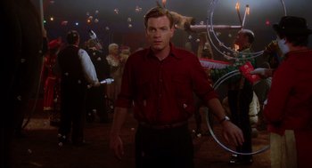Movie still from “Big Fish” (2003), directed by Tim Burton – A man in a red shirt is standing in front of a crowd; Medium shot, Over the shoulder angle