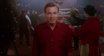 Movie still from “Big Fish” (2003), directed by Tim Burton – A man in a red shirt is smiling for the camera; Medium shot, Over the shoulder angle