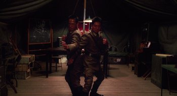 Movie still from “Big Fish” (2003), directed by Tim Burton – A couple of men standing next to each other holding drinks; Medium shot, Low angle