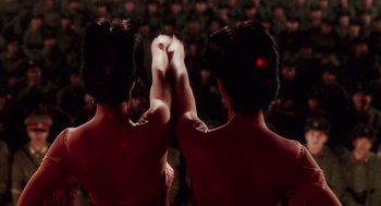 Movie still from “Big Fish” (2003), directed by Tim Burton – Two women in red dresses holding their hands up in front of a group of people; Close Up shot, Low angle