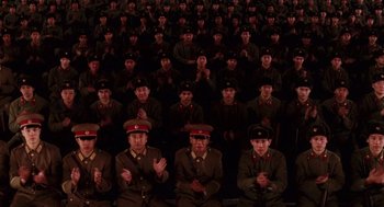 Movie still from “Big Fish” (2003), directed by Tim Burton – A group of men in military uniforms sitting in a stadium; Extreme Wide shot, High angle