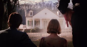 Movie still from “Big Fish” (2003), directed by Tim Burton – A woman standing in front of a white house with green shutters; Wide shot, Low angle