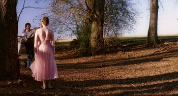 Movie still from “Big Fish” (2003), directed by Tim Burton – A woman in a pink dress standing in front of a tree; Wide shot, Low angle