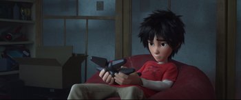 Movie still from “Big Hero 6” (2014), directed by Chris Williams – A boy sitting in a chair holding a remote control; Medium shot, Overhead angle