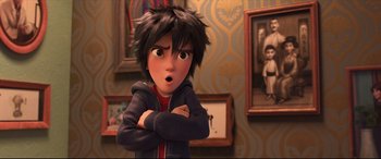 Movie still from “Big Hero 6” (2014), directed by Chris Williams – A young boy with his arms crossed in front of a wall of pictures; Close Up shot, Over the shoulder angle