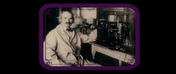 Movie still from “Big Jake” (1971), directed by George Sherman – An old photo of a man sitting in front of a machine; Medium shot, Low angle