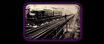 Movie still from “Big Jake” (1971), directed by George Sherman – A man standing on a train track next to train cars; Extreme Wide shot, Low angle