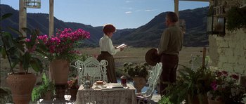 Movie still from “Big Jake” (1971), directed by George Sherman – A man and a woman standing at a table with a book; Wide shot, Over the shoulder angle