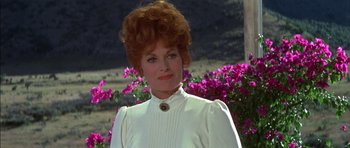 Movie still from “Big Jake” (1971), directed by George Sherman – An older woman in a white dress standing in front of flowers; Close Up shot, Low angle