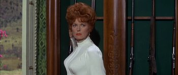 Movie still from “Big Jake” (1971), directed by George Sherman – A woman in a white dress standing in front of a door; Medium shot, Low angle