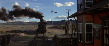 Movie still from “Big Jake” (1971), directed by George Sherman – A steam train traveling down the tracks near a station; Extreme Wide shot, Low angle