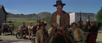 Movie still from “Big Jake” (1971), directed by George Sherman – A man in a cowboy hat is sitting on a horse; Wide shot, Low angle