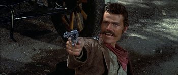 Movie still from “Big Jake” (1971), directed by George Sherman – A man holding a gun in his hand; Close Up shot, Low angle