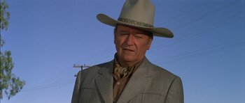 Movie still from “Big Jake” (1971), directed by George Sherman – A person wearing a suit and a cowboy hat; Close Up shot, Low angle