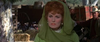 Movie still from “Big Jake” (1971), directed by George Sherman – An older woman wearing a green dress and a green head scarf; Close Up shot, Over the shoulder angle