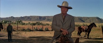 Movie still from “Big Jake” (1971), directed by George Sherman – A man in a suit and a cowboy hat on a horse; Medium shot, Low angle
