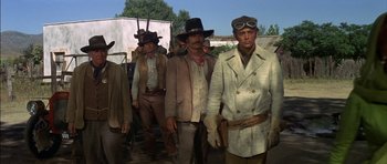 Movie still from “Big Jake” (1971), directed by George Sherman – A group of men standing next to each other on a street; Medium shot, Low angle