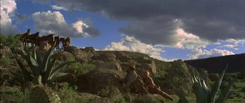 Movie still from “Big Jake” (1971), directed by George Sherman – A man and a woman sitting on top of a hill; Wide shot, Low angle