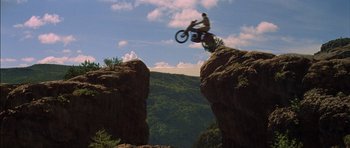 Movie still from “Big Jake” (1971), directed by George Sherman – A person on a motorcycle jumping over a cliff; Wide shot, Low angle